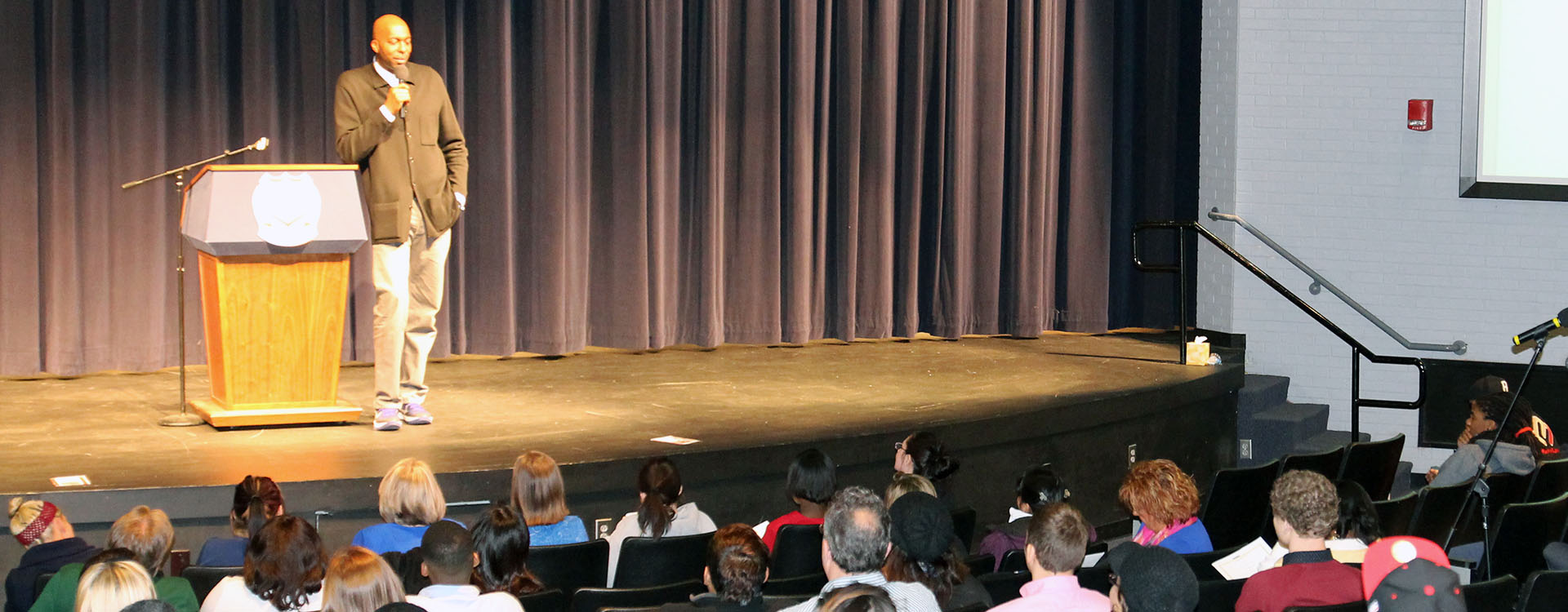 public speaker standing on stage in front of audience