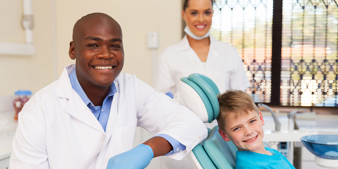 Dentist, dental assistant, and child patient preparing for treatment