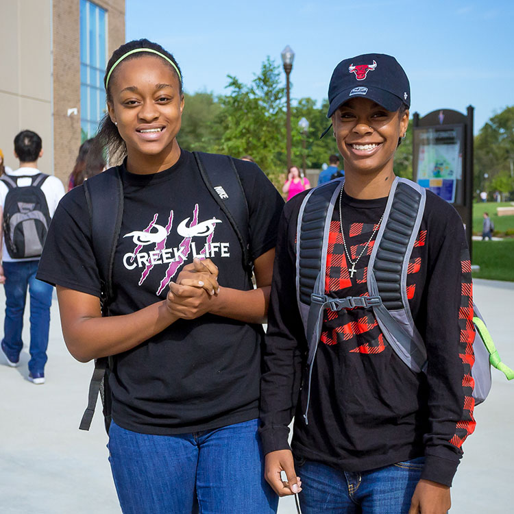 two students standing and smiling