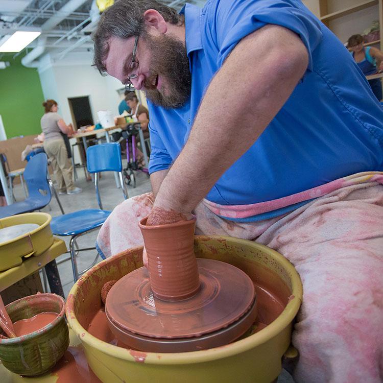 student working with clay on a pottery wheel