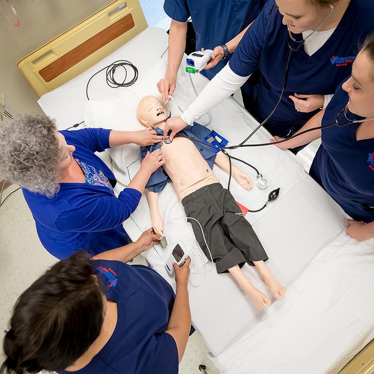 nursing students working on a practice mannequin